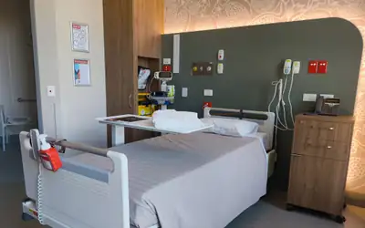 Single-bed private patient room with window and bedside cabinet in a modern hospital