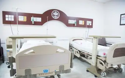 Two-bed hospital room with adjustable beds and bedside tables