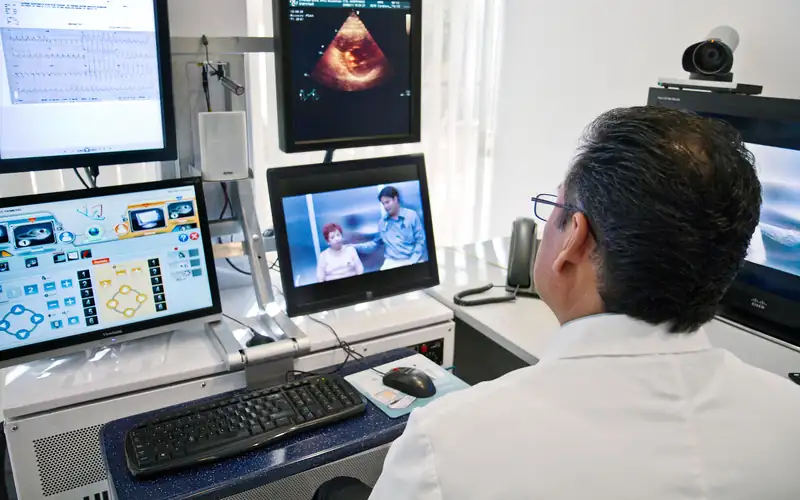 Doctor at a telemedicine workstation reviewing scans during a video consultation